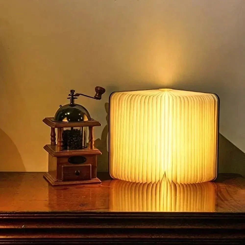 Faltbare Buchlampe aus Holz und Papier mit warmem Licht