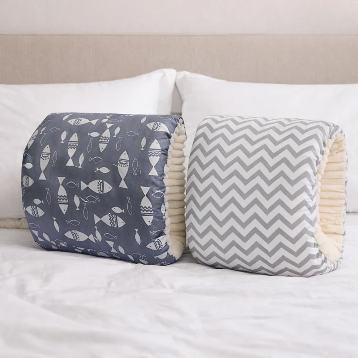 Two Arm-Stillkissen pillows with fish and chevron patterns on white bed