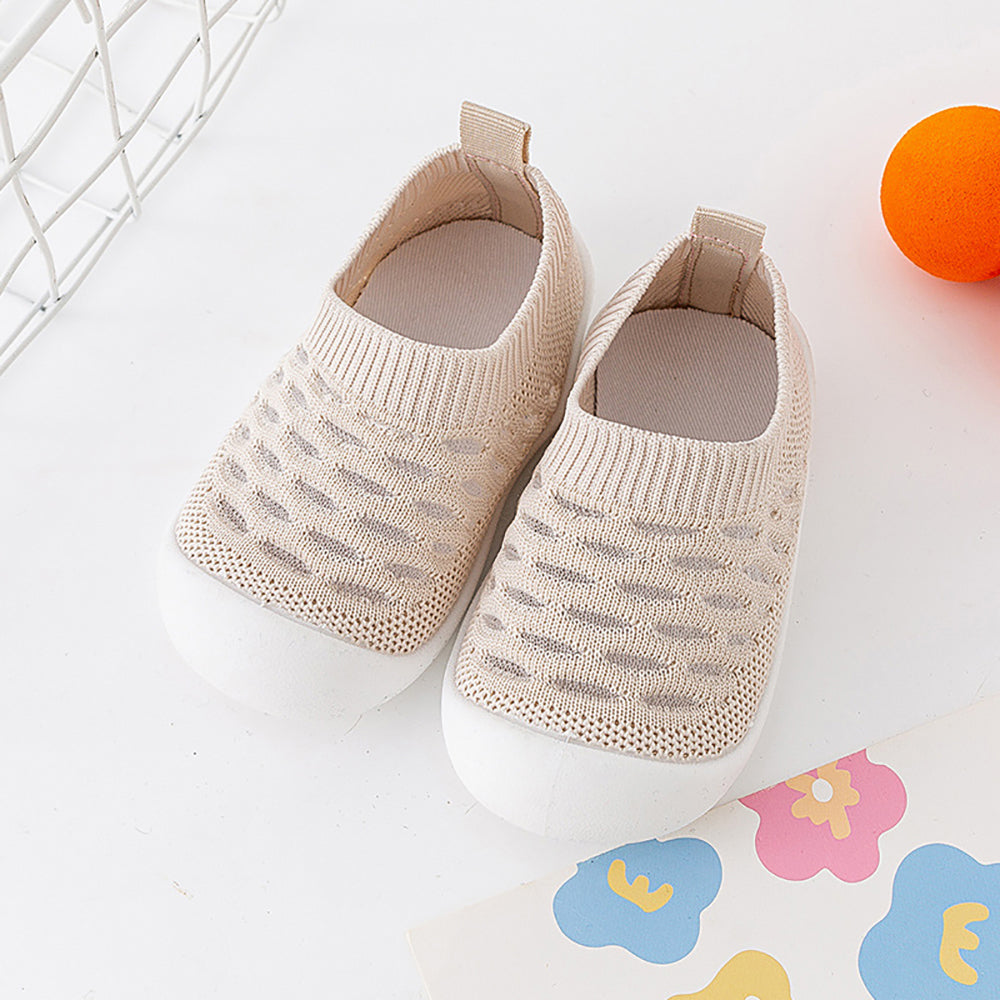 Beige breathable baby shoes with ribbed cuffs on colorful alphabet mat